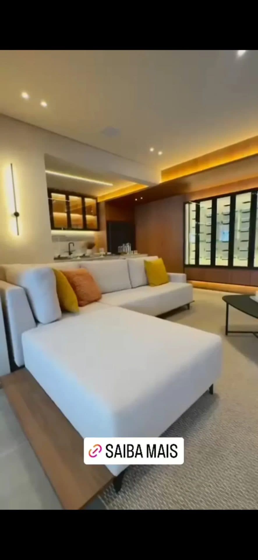 Sala de estar com sofá em L, iluminação embutida e marcenaria planejada.